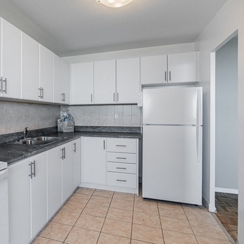 a white kitchen with white cabinets and a white refrigerator